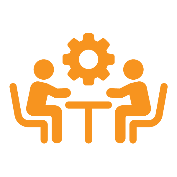 Two people sit at a table facing each other with a gear icon above them, suggesting collaboration or a meeting focused on teamwork or problem-solving.